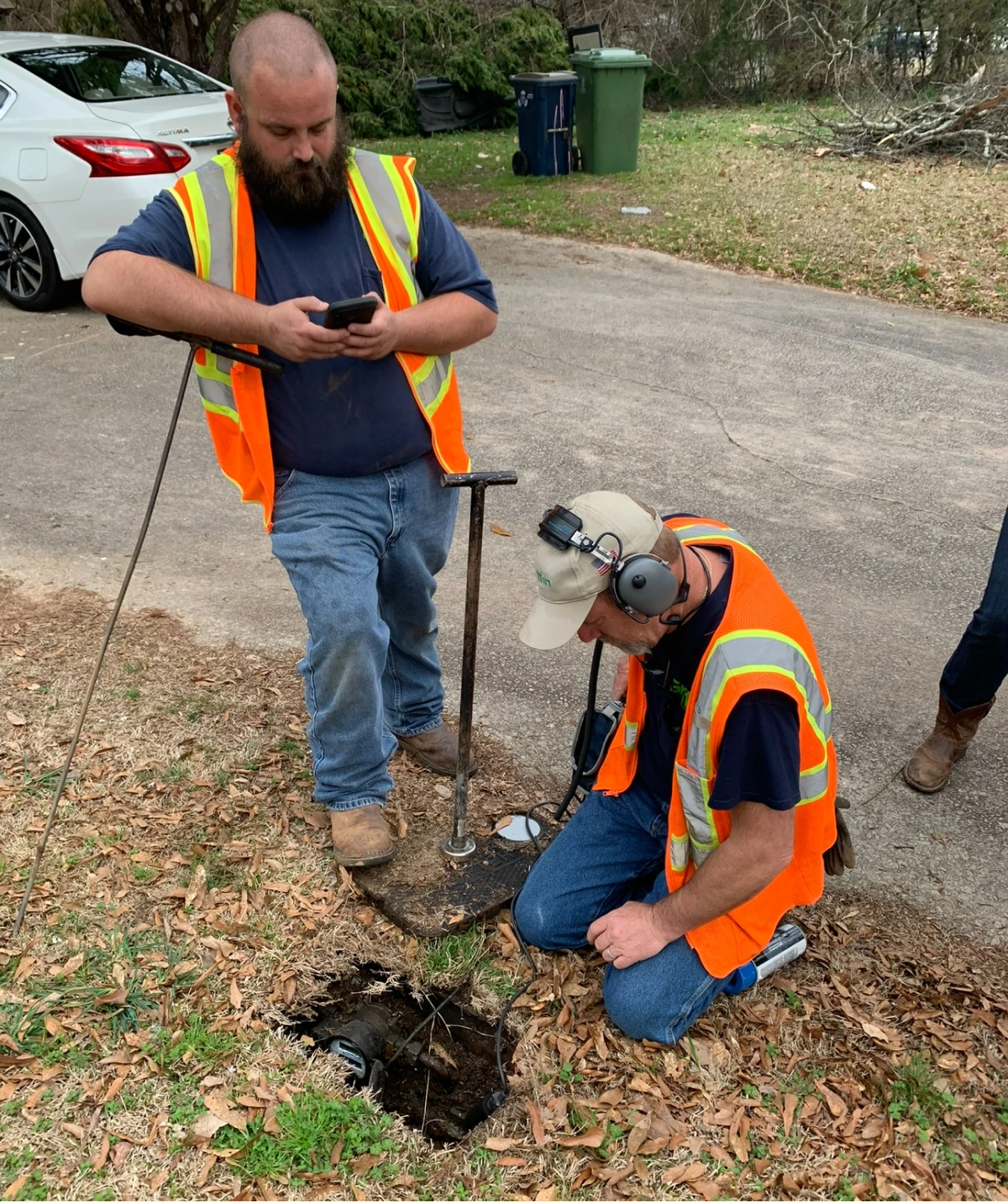Workers inspecting underground pipes with equipment